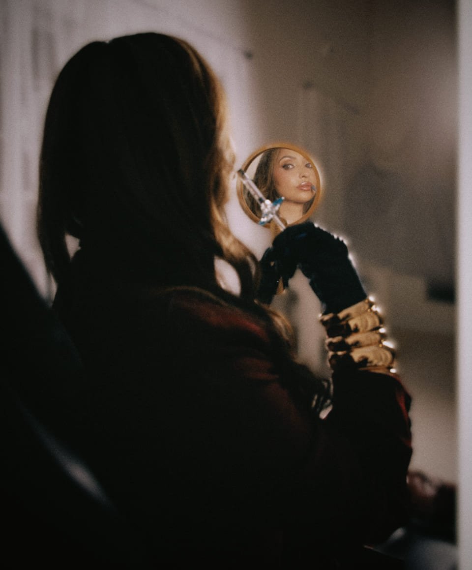 Desiree Antonelli viewing herself in a hand mirror